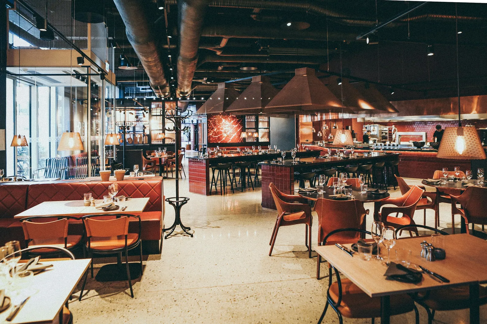 A warm, industrial-style restaurant dining room set for service